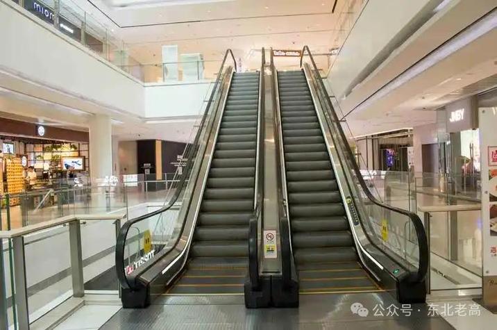 {“title”: “不用爬楼，站在上面就能自己上下的自动扶梯——现代城市的高科技缩影”, “content”: “清晨的地铁站里，人群鱼贯而入，站在扶梯上便能平稳地升上站厅，几乎没有人需要自己迈步爬楼。这样一种看似平常的装置，正是现代城市中极具代表性的高科技产品——自动扶梯。\n\n自动扶梯之所以能”自己上下“，核心在于一套精密的机械与电气系统。它由梯级、牵引链条、导轨、驱动主机、制动器、控制柜以及安全保护装置等部分组成。电动机通过减速机驱动主轮，带动两条牵引链条循环运转，梯级便沿导轨做闭合循环运动。扶